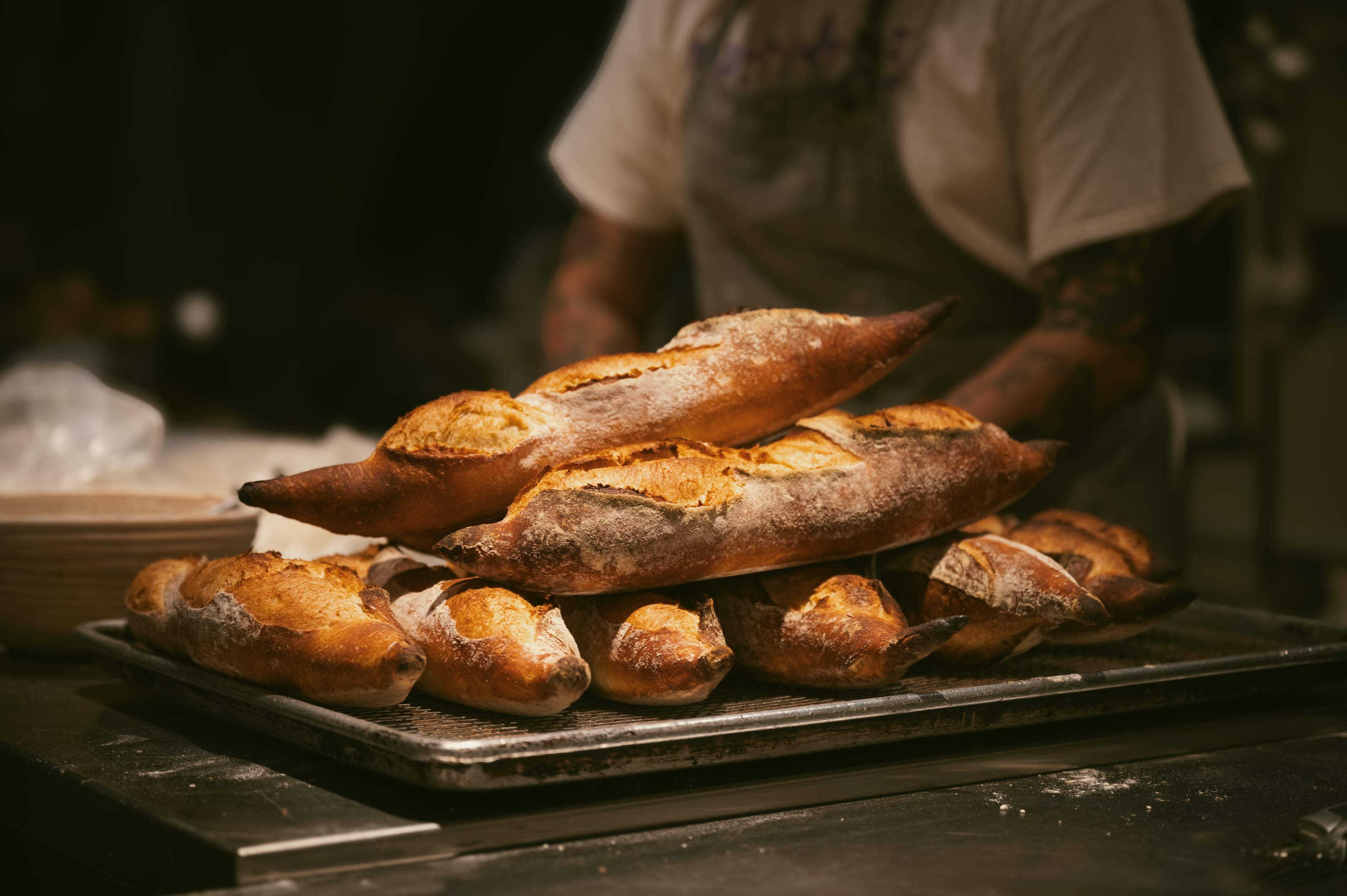 Fresh baguettes and rustic loaves on a baker's tray at LoDough Bakery