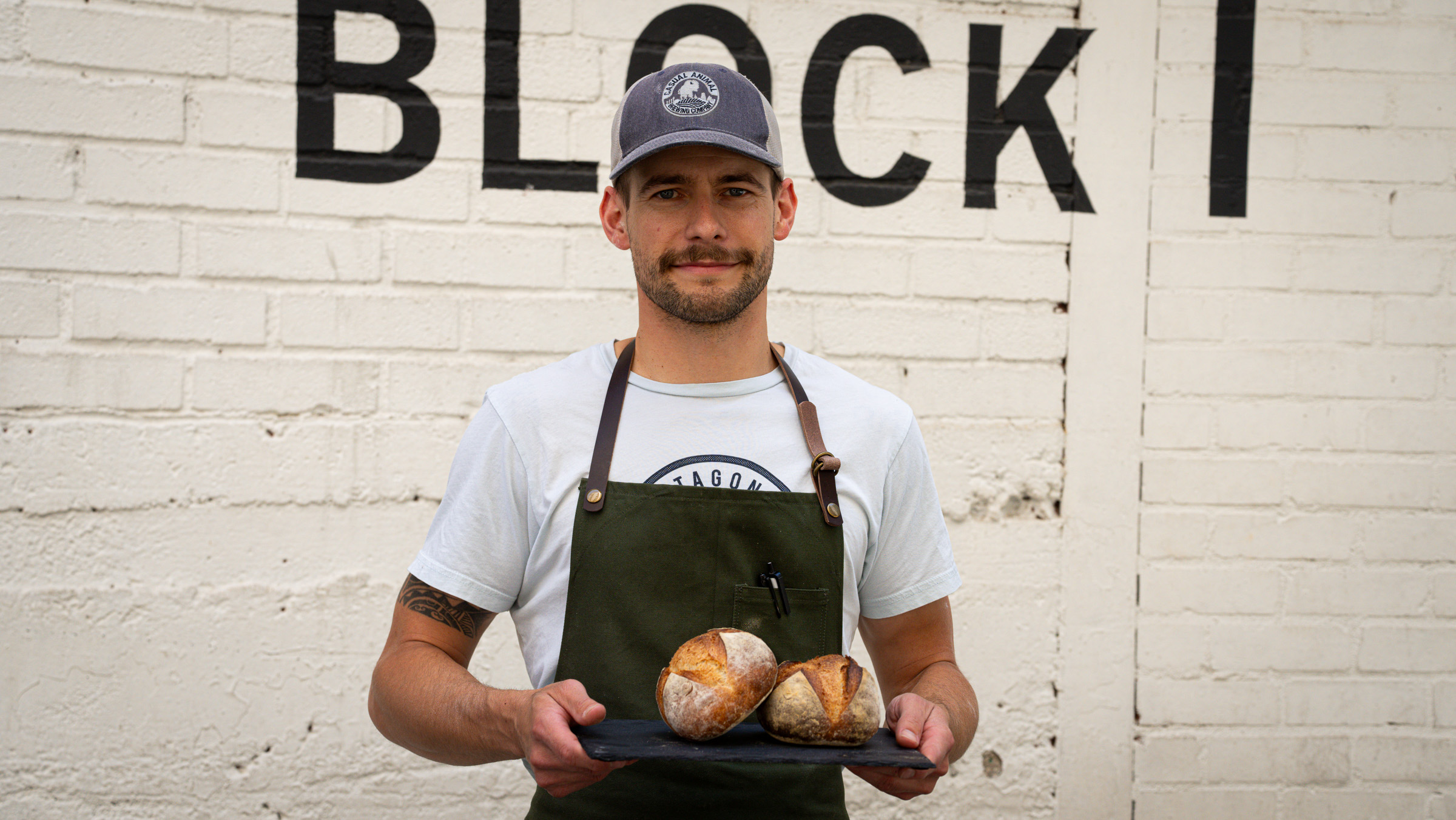 A LoDough baker holding two fresh loaves